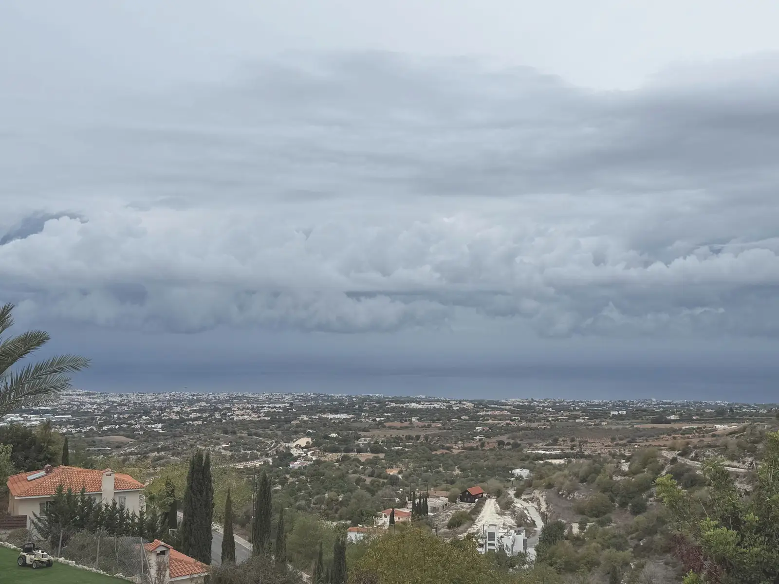 Σύννεφα καταιγίδας πάνω από την ακτή και τη θάλασσα, όπως φαίνονται από μια πλαγιά πάνω από τα σπίτια της παραλίας